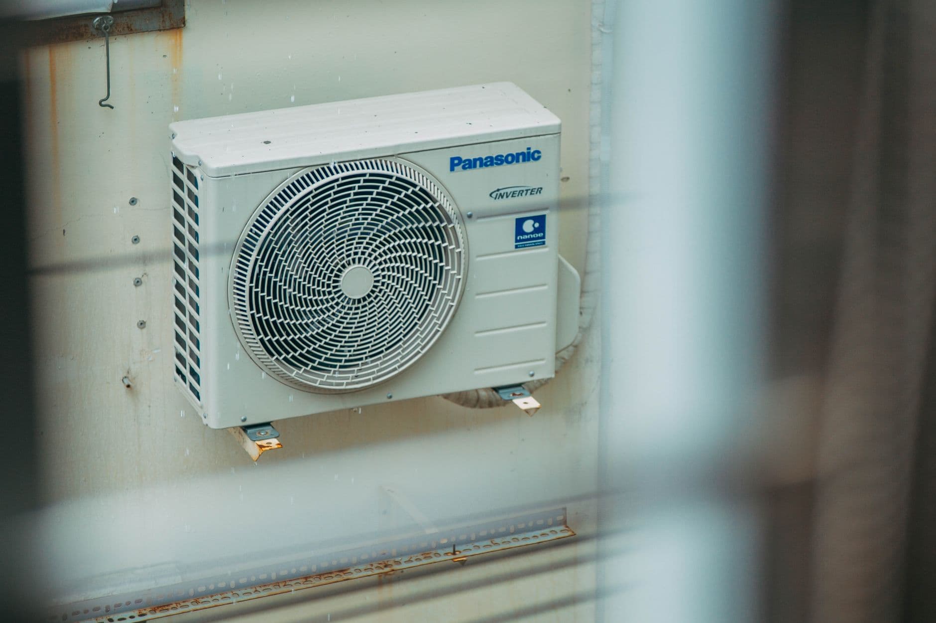 HVAC technician inspecting a residential outdoor condenser unit during shoulder season