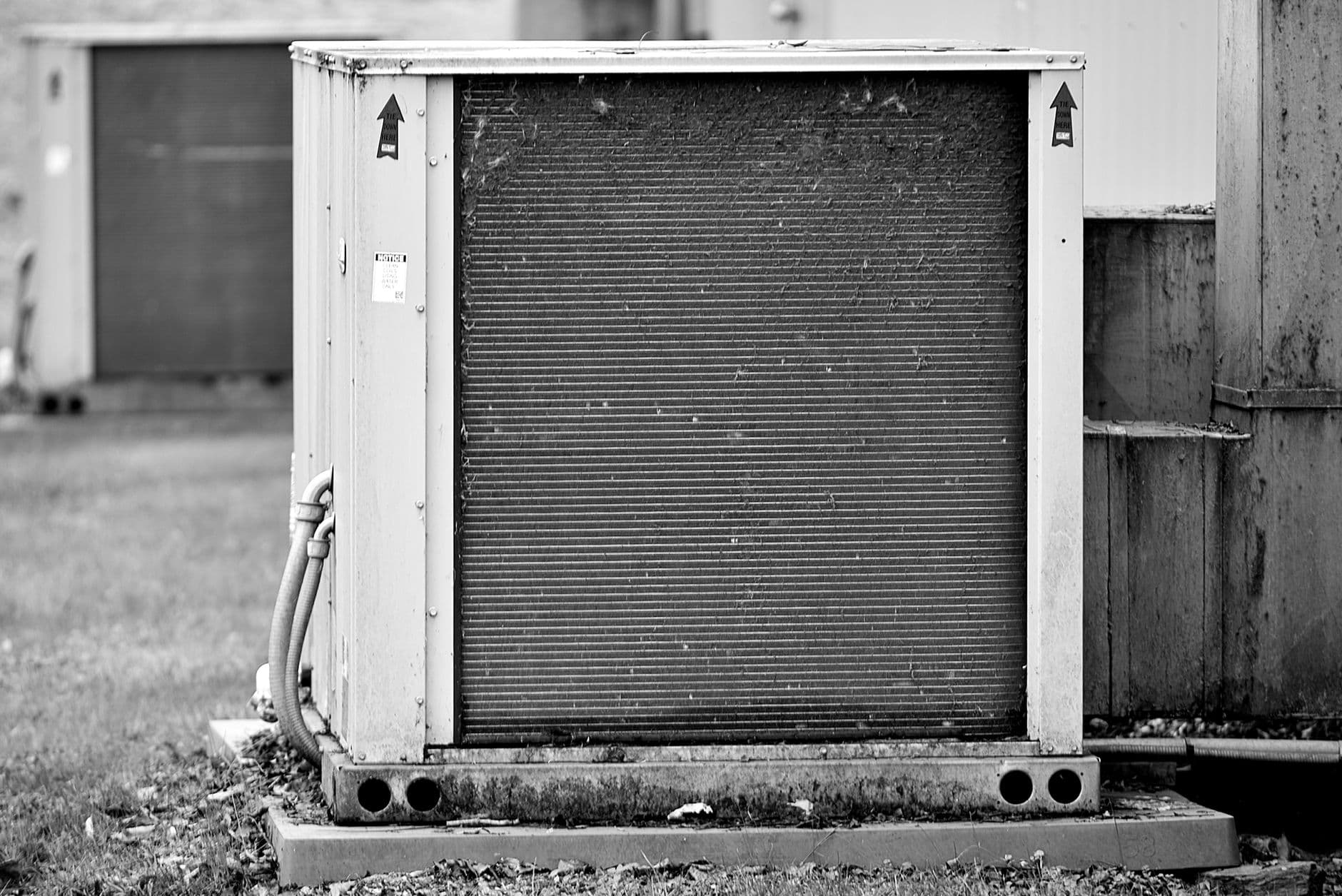 HVAC technician inspecting an outdoor air conditioning unit at a residential property