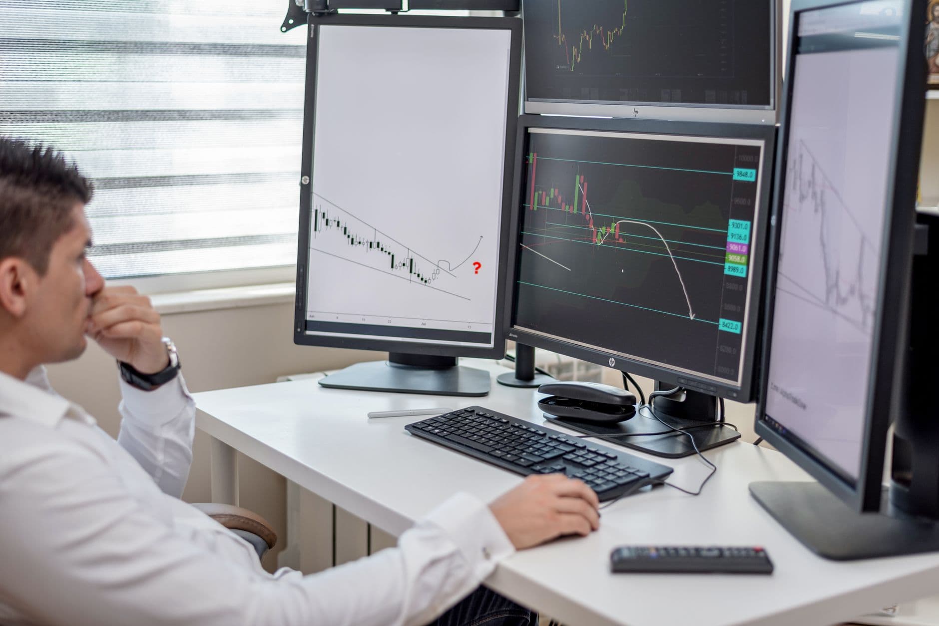 A freight broker reviewing shipper data on multiple monitors in a logistics office