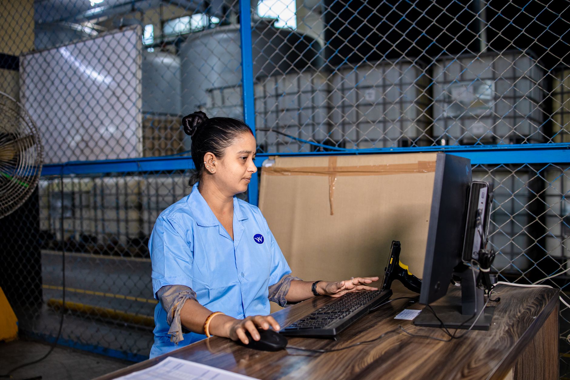 Logistics coordinator at a warehouse desk reviewing data on a computer screen